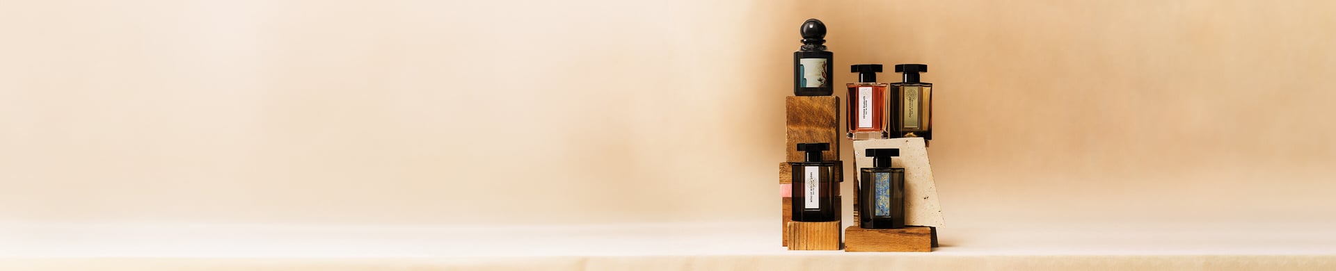 Five fragrance bottle displayed on wooden blocks on a beige background.jpg