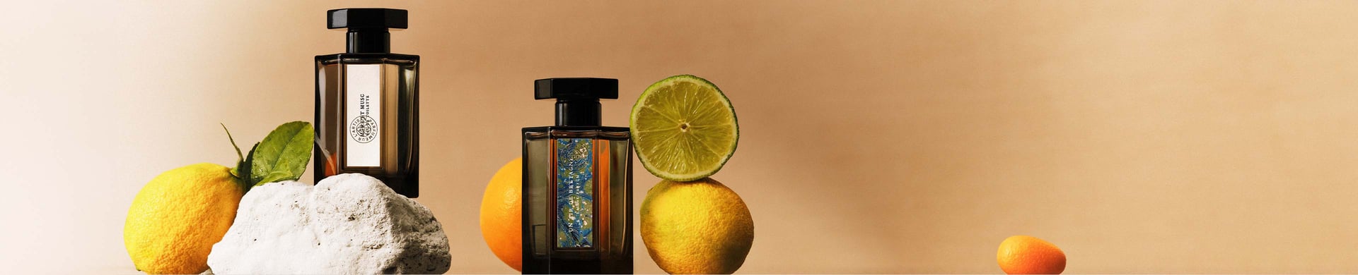 Two perfume bottles surrounded by citrus fruits on a brown background