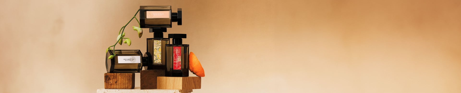 Four fragrance bottles on wooden blocks on a beige background